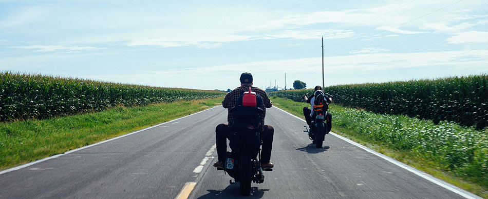 Two motorcycles on the road between cornfields
