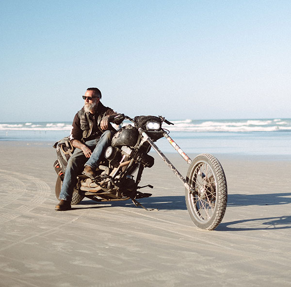 Charlie Weisel, the Traveling Chopper, on his motorcycle on the beach