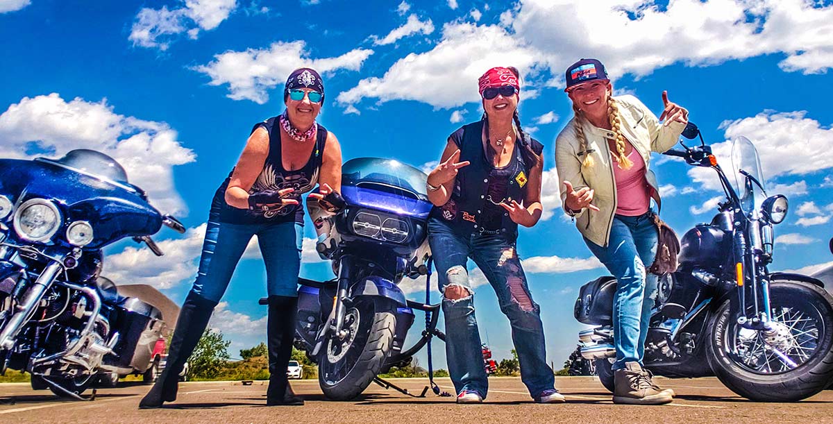 Audrey Paulus, center, with 2 female bikers next to their motorcycles