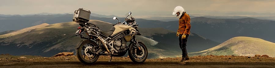 Motorcyclist looking at bike by Colorado mountainscape